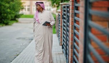 Saudi Arabian man posed on street against modern building with tablet at hands