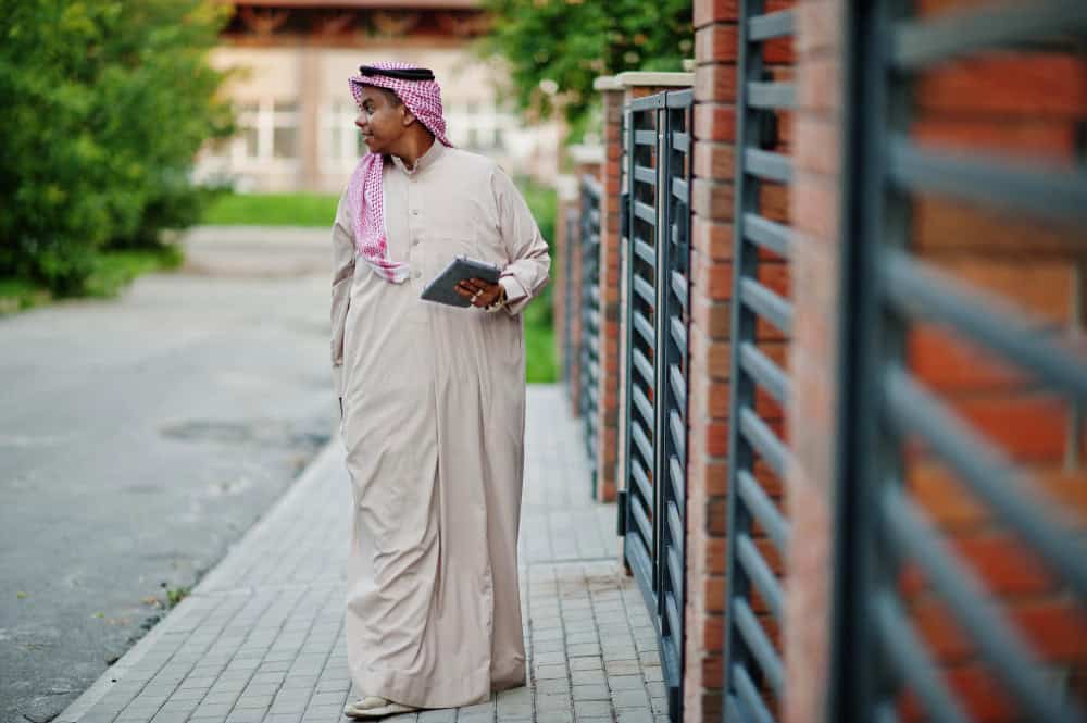 Saudi Arabian man posed on street against modern building with tablet at hands